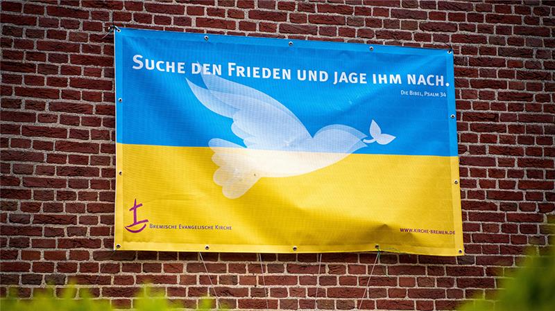 Eine ukrainische Flagge mit dem Bibelvers "Suche den Frieden und jage ihm nach" hängt an der St. Markus-Gemeinde. Foto: Sina Schuldt/dpa