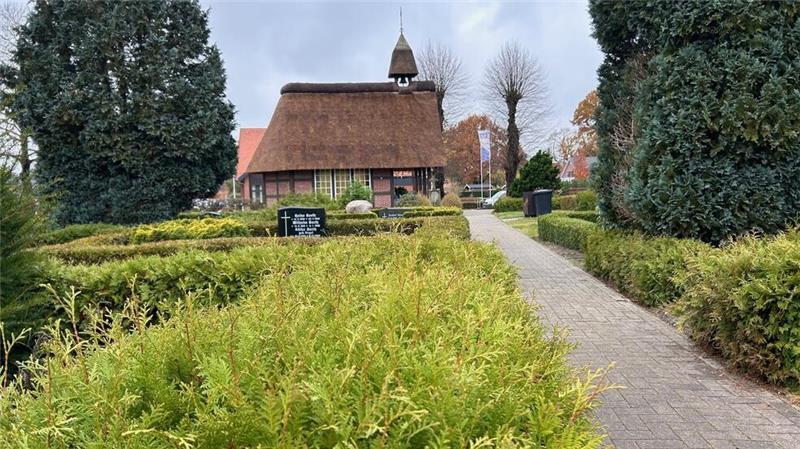 Friedhöfe in Hammah: Zu großer Pflegeaufwand Die Friedhofskapelle Hammah hat ein Reetdach und ein kleines Glockentürmchen. Ein gepflastertert Weg führt zur Kapelle. Der Weg ist von Hecken gesäumt, einige sind gestutzt, andere nicht.