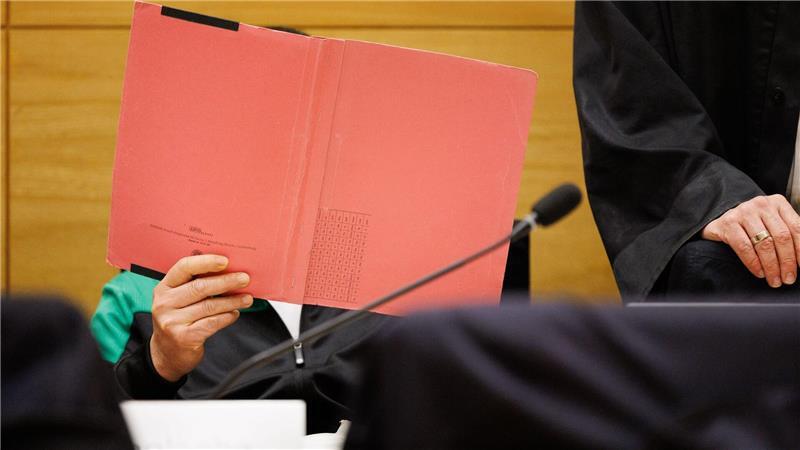 Einer der Angeklagten am Landgericht Bielefeld sitzt neben seinem Verteidiger und verdeckt sein Gesicht.