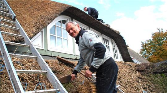 Einer der wenigen seiner Zunft: Reetdachdeckermeister Helmut Müller in Rutenbeck - oben über der Gaube arbeitet sein Sohn Christoph.