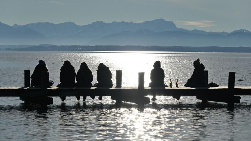 Bilder des Tages Einfach nur sein: Ausflügler sitzen auf einem Steg am Starnberger See und genießen den Blick auf die Zugspitze.