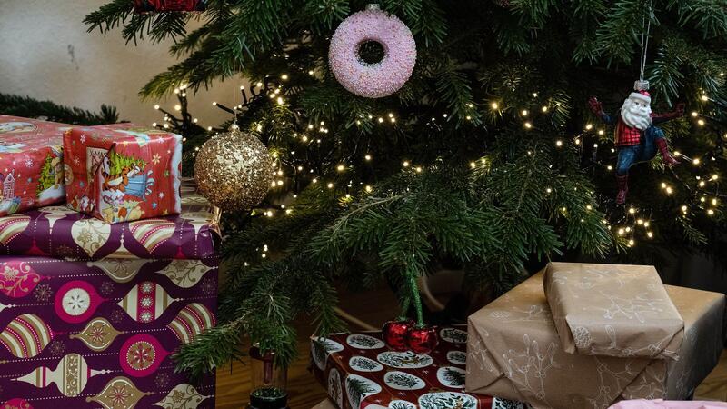 Eingepackte Geschenke liegen unter einem geschmückten Weihnachtsbaum. Die Menschen in Deutschland wollen in diesem Jahr bei den Präsenten sparsamer sein.