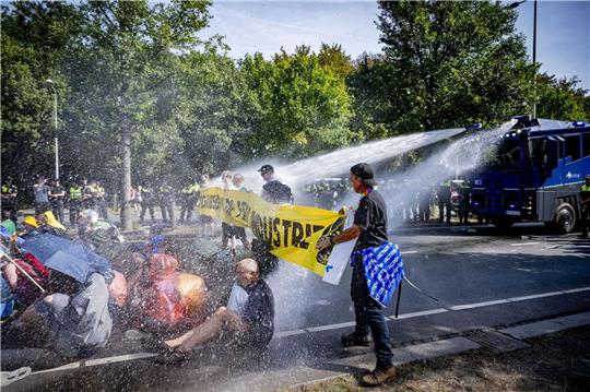 Einsatz von Wasserwerfern gegen Klimaaktivisten, die eine Straße blockieren.