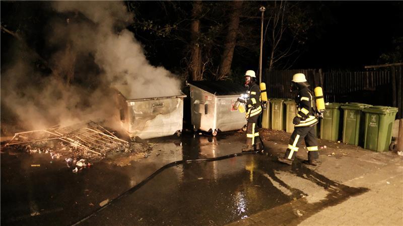 Einsatzkräfte der Feuerwehr Burweg löschen brennenden Abfall-Container.