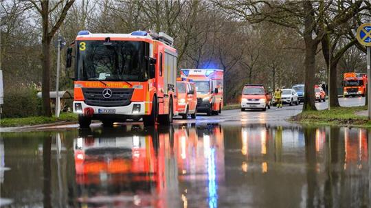 Einsatzkräfte der Feuerwehr Hannover stehen bei einem Einsatz auf einer überfluteten Straße.