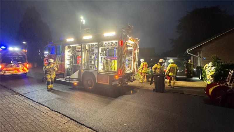 Einsatzkräfte der Feuerwehr Wiepenkathen vor dem brennenden Haus.