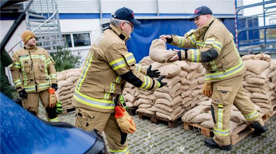 Einsatzkräfte der Feuerwehr geben auf einem Parkplatz zahlreiche Sandsäcke an die Anwohner im Bereich der Hunte am Achterdiek aus. Die Hochwasserlage bleibt in vielen Regionen Niedersachsens angespannt.