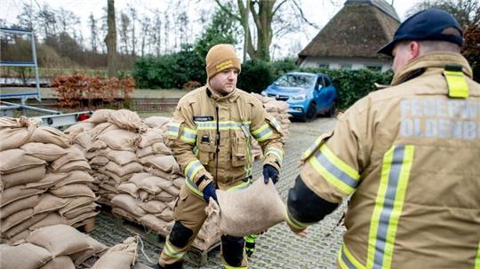 Einsatzkräfte der Feuerwehr geben auf einem Parkplatz Sandsäcke an die Anwohner im Bereich der Hunte am Achterdiek aus.