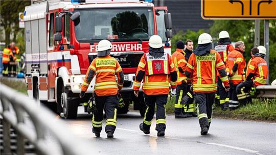 Einsatzkräfte der Feuerwehr stehen bei einem Großbrand in einem Braunschweiger Industriegebiet.