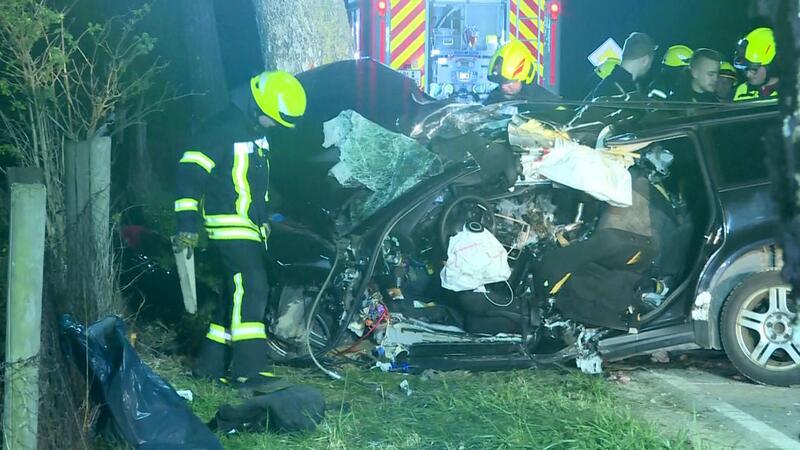 In diesem Autowrack sterben drei junge Menschen Einsatzkräfte der Feuerwehr stehen neben dem völlig zerstörten VW.