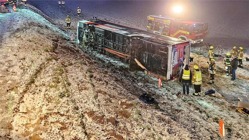 Einsatzkräfte der Feuerwehr stehen neben einem umgekippten Linienbus an der Unfallstelle im Landkreis Ludwigsburg.