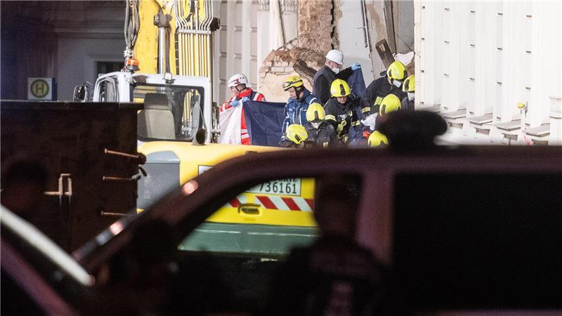 Einsatzkräfte der Feuerwehr tragen hinter Sichtschutz eine Leiche aus dem Trümmerfeld eines eingestürzten Hauses in Görlitz. 