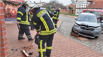 Einsatzkräfte der Feuerwehren und Polizei am Unfallwagen vor der Sparkasse in Himmelpforten.
