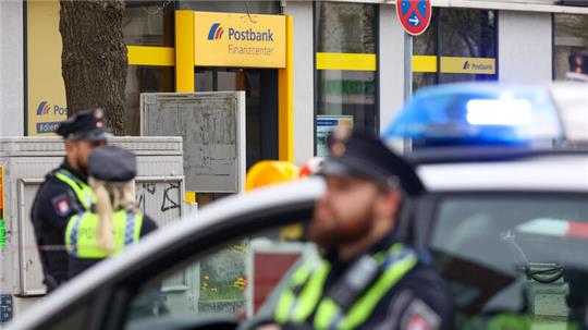 Einsatzkräfte der Hamburger Polizei stehen bei einem Einsatz vor einer Postbank-Filiale in Hamburg-Lurup. Eine Postbankfiliale im Hamburger Lurup-Center sowie umliegende Straßen sind am Dienstagmorgen weiträumig abgesperrt und Sprengstoff-Entschärfer angefordert worden.