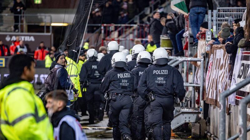 POlizei: Zwei Tatverdächtige nach Böllerwurf in Augsburg Einsatzkräfte der Polizei laufen auf den Fanblock der Hannoveraner zu.
