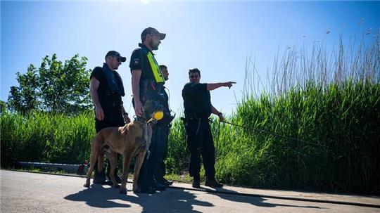 Einsatzkräfte der Polizei stehen bei der Suche nach dem vermissten Arian mit einem Spürhund an der Oste.