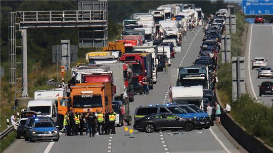 Einsatzkräfte der Polizei stehen nach einem Unfall vor einem Stau auf der A7 bei Neumünster.