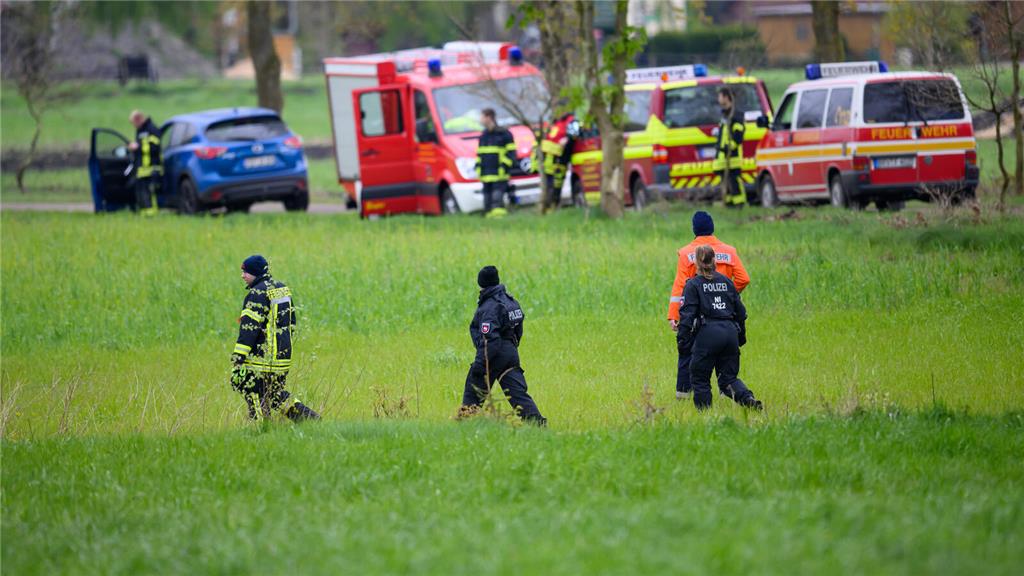Einsatzkräfte der Polizei und Feuerwehr auf einem Feld im Einsatz. 