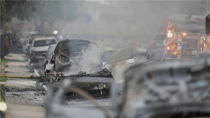 Einsatzkräfte fahren an beschädigten Fahrzeugen am Schauplatz des Absturzes eines Kleinflugzeugs in einem Stadtviertel von San Diego vorbei. 