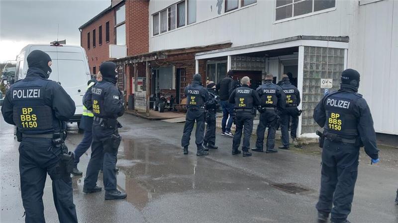 Auch in Stade: Razzien gegen Schleuserbande - Fünf Festnahmen Einsatzkräfte sammeln sich vor einem Gebäude.