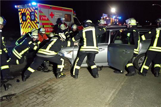 Einsatzkräfte schieben ein Unfallfahrzeug mit vereinten Kräften von der Straße. Foto: Rolf Hillyer-Funke/Feuerwehren Samtgemeinde Oldendorf-Himmelpforten