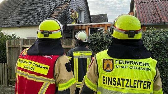 Einsatzkräfte untersuchen sorgfältig das Dach des Einfamilienhauses auf versteckte Glutnester. Dafür müssen auch Dachpfannen entfernt werden.