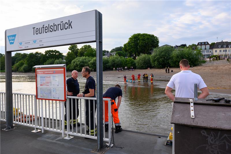 Einsatzkräfte von Feuerwehr, DLRG und Polizei stehen während der Suche auf dem Anleger "Teufelsbrück" und am Ufer der Elbe. Ein 13-jähriger Nichtschwimmer ist am Samstagabend in Hamburg-Nienstedten in der Elbe untergegangen. Foto: Jonas Walzberg/dpa