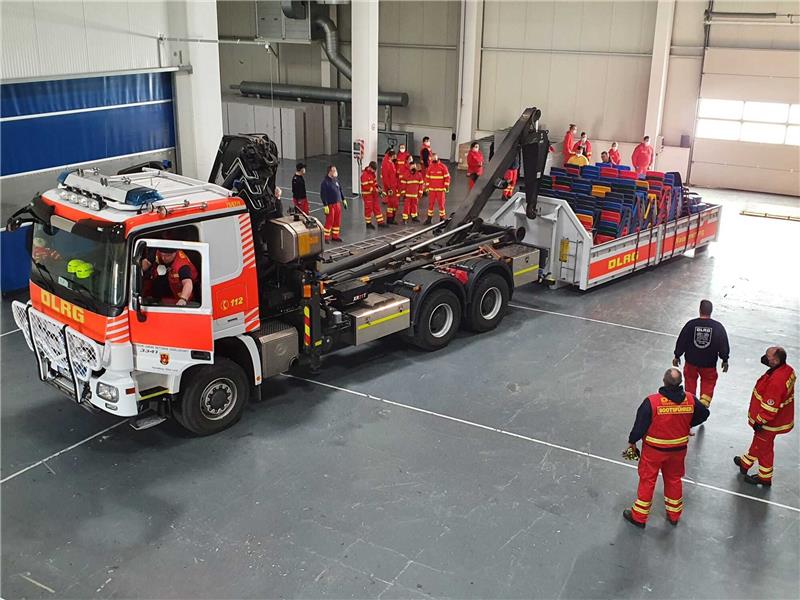 Einsatzkräfte von Landkreis und Deutscher Lebensrettungsgesellschaft transportieren Material in die Gewerbehalle in Stade-Ottenbeck, die als Notunterkunft hergerichtet wird. Am kommenden Wochenende soll der Ausbau weitergehen. Foto: Deutsche Lebensrettungsgesellschaft (Bohmbach)