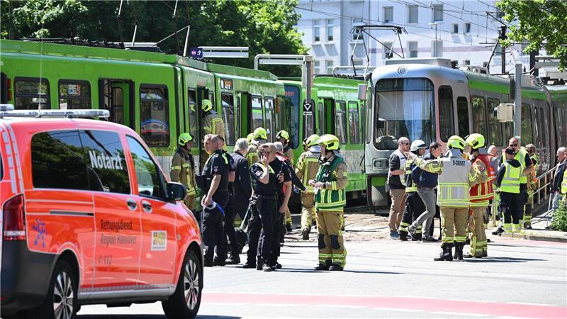 Einsatzkräfte von Polizei und Feuerwehr stehen nach einem Unfall neben zwei Stadtbahnen.
