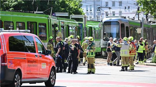 Einsatzkräfte von Polizei und Feuerwehr stehen nach einem Unfall neben zwei Stadtbahnen.