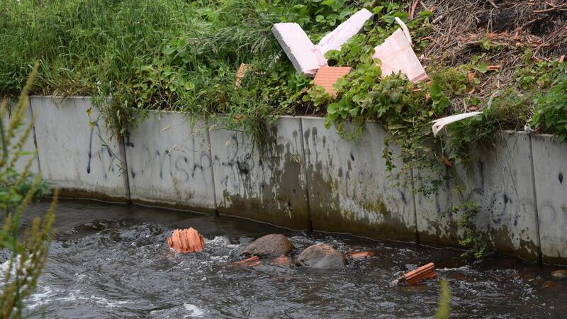 Einzelne Steine und anderer Bauschutt fallen von der Baustelle zum Abbruch des Lidl-Marktes in Altkloster in den Wasserlauf der Fischautobahn. Ein Fangzaun hätte das verhindern können.