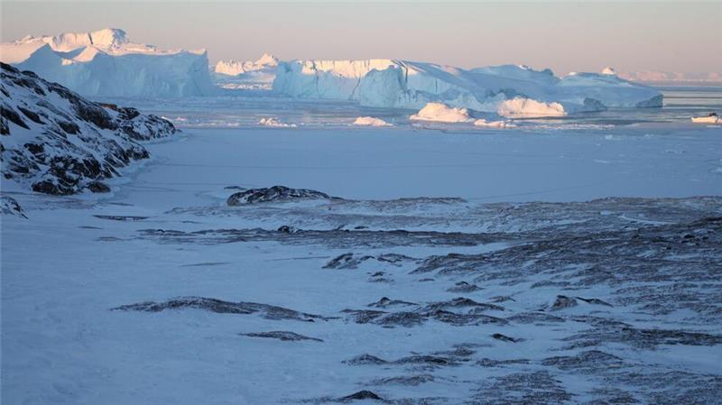 Was Grönlands Rohstoffe für die EU bedeuten Eisberge ragen im Ilulissat-Eisfjord hinter einer verschneiten Gesteinslandschaft in die Höhe.