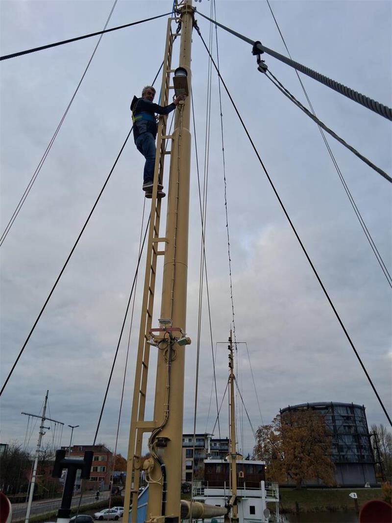 Hingucker in Blau: MS Greundiek leuchtet in der dunklen Jahreszeit Elektriker Bernd Hagenah bei der Montage im Mast.