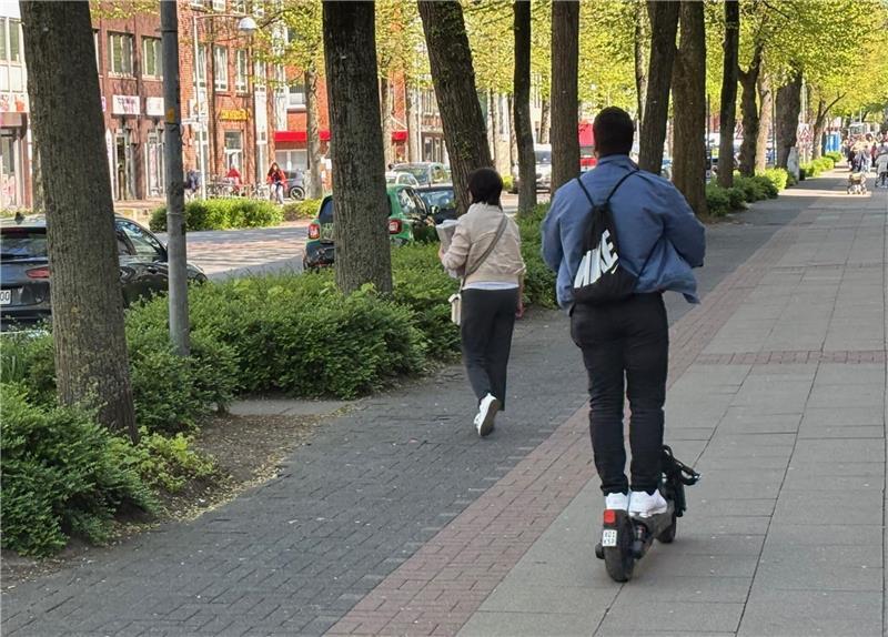Elektrisch betriebene Roller gehören mittlerweile zum Bild in Buxtehude. Auf diesem Foto steht eine unaufmerksame Fußgängerin auf dem Radweg in der Bahnhofstraße einem E-Scooter-Fahrer im Weg, sodass er auf den Fußweg ausweicht.