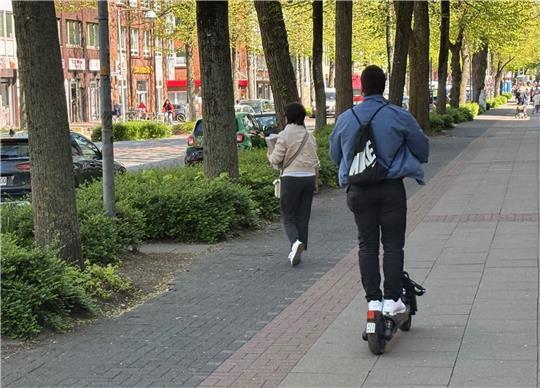 Elektrisch betriebene Roller gehören mittlerweile zum Bild in Buxtehude. Auf diesem Foto steht eine unaufmerksame Fußgängerin auf dem Radweg in der Bahnhofstraße einem E-Scooter-Fahrer im Weg, sodass er auf den Fußweg ausweicht.