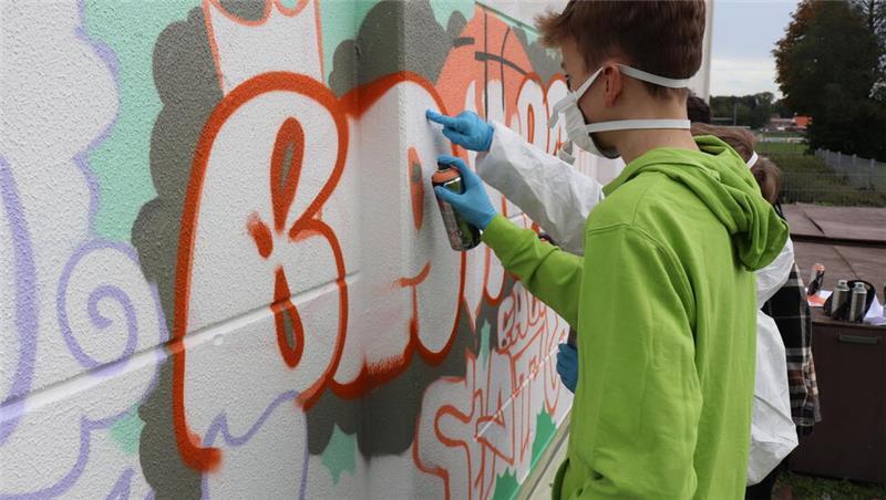 Elias füllt mit der Sprühflasche die Schrift für Basketball aus.