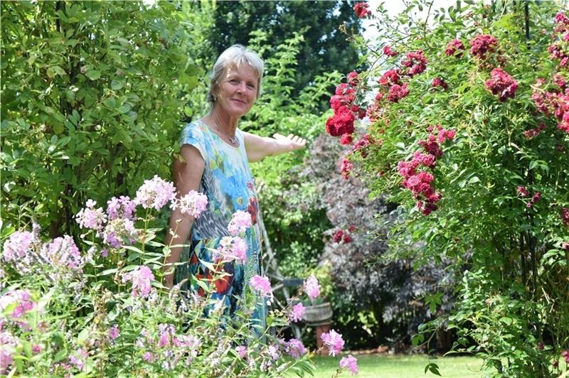 Elke Breitenfeld steht in ihrem Rosentorbogen, er führt von der Terrasse in den Garten. Fotos: Battmer