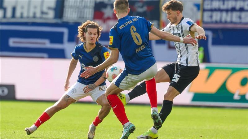 Holstein Kiel mit Punktgewinn bei Walter-Comeback Elversbergs Lukas Petkov (r) im Duell mit den Kielern John Tolkin (l) und Marko Ivezic.