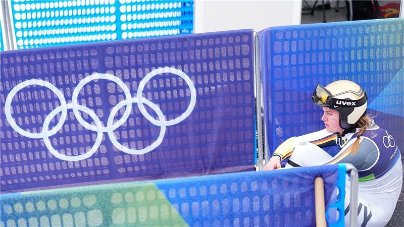 Emma Aicher sitzt nach ihrem Aus im Super-G frustriert im Zielbereich von Cortina d’Ampezzo.