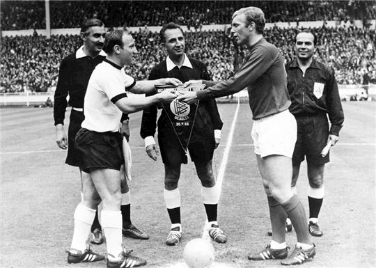 Englands Kapitän Bobby Moore (2.v.r.) tauscht mit dem westdeutschen Kapitän Uwe Seeler (2.v.l.) vor Beginn des Endspiels der Fußballweltmeisterschaft in Wembley, die Wimpel aus.  Foto: Uncredited/BIPPA/dpa