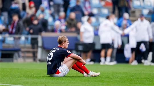 Entäuscht sitzt der Kieler Kasper Davidsen nach dem Abpfiff auf dem Rasen.