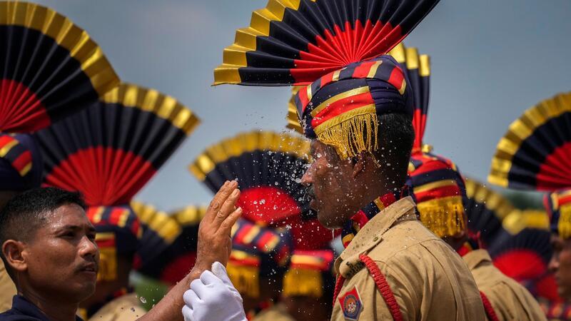 Erfrischung bei Parade in Indien: Ein Zivilschützer bespritzt ein Mitglied der Assam-Polizei mit Wasser, während sie an einem heißen sonnigen Tag an einer Parade zum Unabhängigkeitstag teilnehmen.