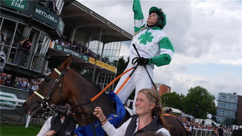 Erinnerung an ihren Vater: Nina Baltromei zeigt nach ihrem historischen Sieg beim deutschen Galopp-Derby mit dem Zeigefinger gen Himmel.