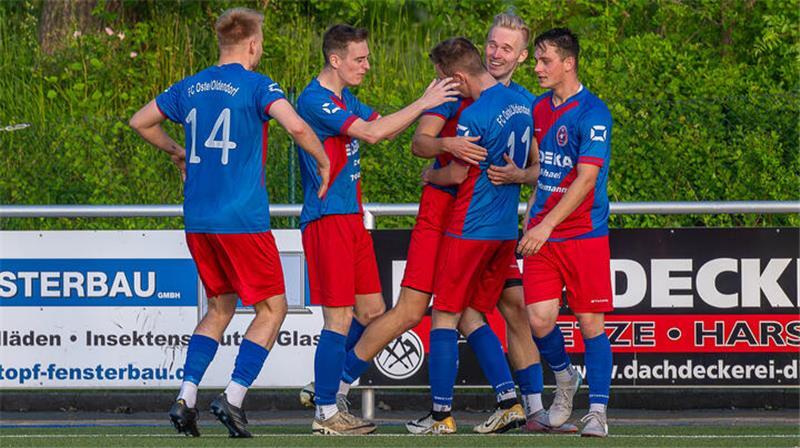 Spieler des FC Oste/Oldendorf in rot-blauen Trikots kommen zum Jubel nach dem Tor von Philipp Elfers.