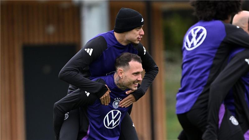 Erst Huckepack dann Doppelpack? Beim Training der Fußball-Nationalmannschaft vor dem WM-Quali-Spiel gegen Luxemburg trägt David Raum Aleksandar Pavlovic auf den Schultern.