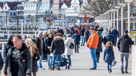 Erste Besucher sind am Samstagvormittag auf der Promenade von Travemünde unterwegs.