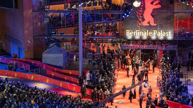 Erste Gäste stehen während der Eröffnung der 74. Berlinale auf dem roten Teppich vor dem Berlinale-Palast.