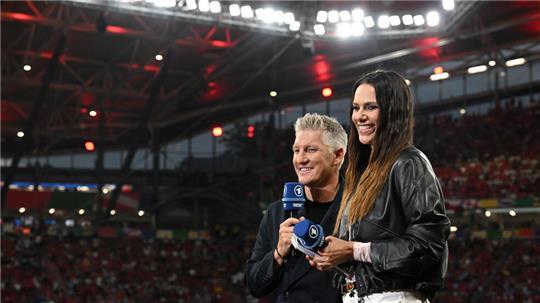 Esther Sedlaczek, Fernsehmoderatorin, und der frühere Nationalspieler Bastian Schweinsteiger stehen als ARD Moderationsteam im Stadion. 2028 zeigen ARD und ZDF wieder EM-Spiele.