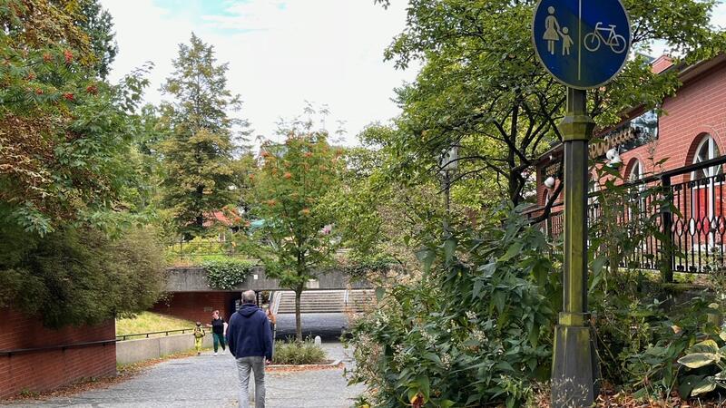 Etwas erhöht weist das Verkehrsschild Fußgängern und Radfahrern die Seiten zu: Radfahrer rechts, Fußgänger links. Eine eher ungewöhnliche Einteilung. Meist sollen Radfahrer sich links halten.