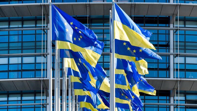 Europäische und ukrainische Flaggen wehen vor dem Europäischen Parlament in Straßburg. Die EU-Kommission erklärt die positive Empfehlung für das osteuropäische Land damit, dass die noch ausstehenden Reformen bereits auf den Weg gebracht seien.